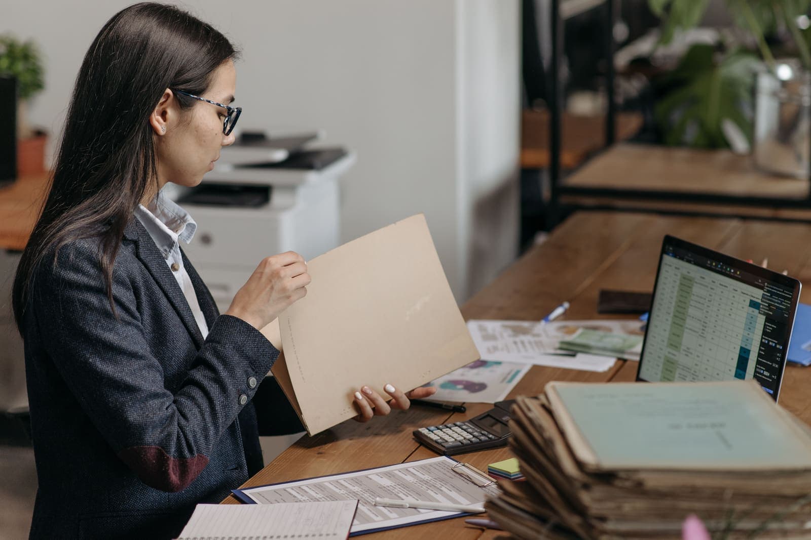 Employée examinant des documents à son bureau, devant un ordinateur portable