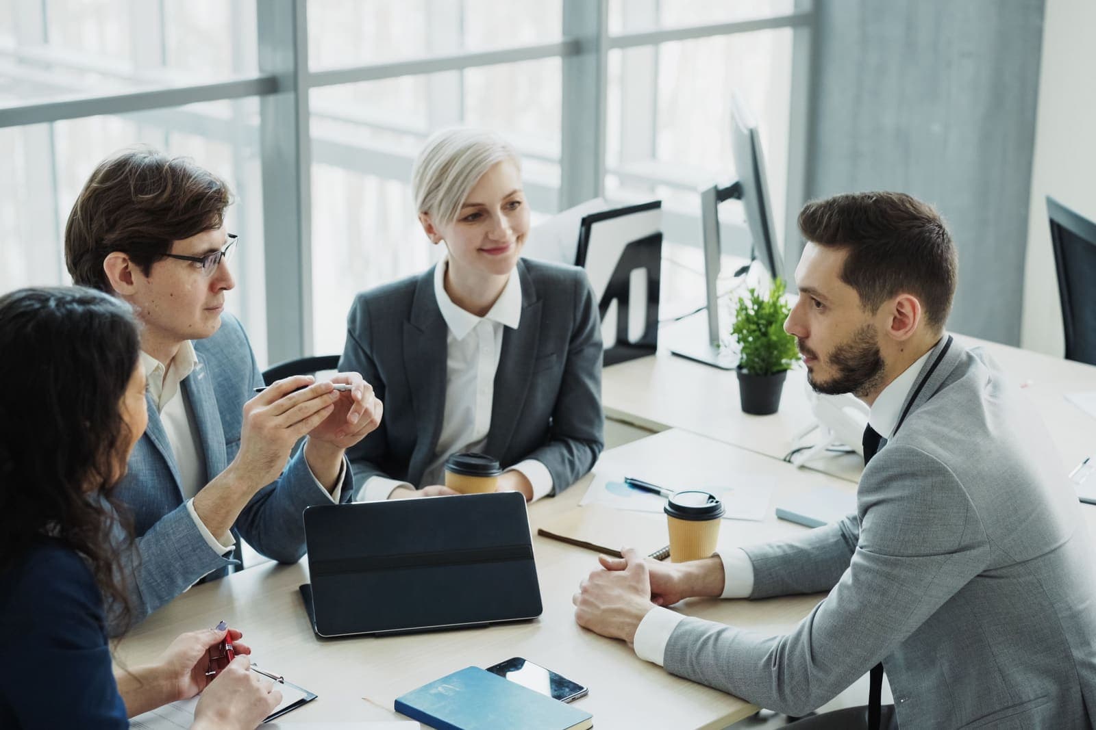 Équipe de professionnels en réunion autour d'une table dans un bureau lumineux